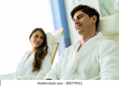 A handsome man and a woman relaxing in a chair at a spa