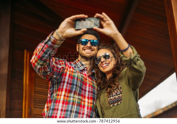 Handsome\
man and woman in wooden cabin with mobile\
phone.