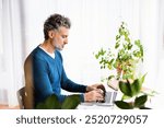 Handsome man working from home office, sitting at desk with laptop, smiling. Telecommuting and home office.