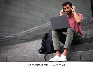  Handsome man working with laptop on city street. Man using his laptop while sitting on stairs outdoors.