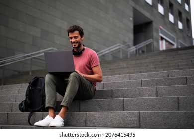 Handsome man working with laptop on city street. Man using his laptop while sitting on stairs outdoors - Powered by Shutterstock