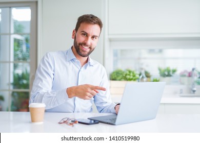 Handsome man working using computer laptop and drinking a cup of coffee very happy pointing with hand and finger - Shutterstock ID 1410519980