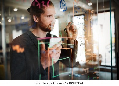 Handsome man working and writing on glass board in office. Business, technology, research concept - Powered by Shutterstock