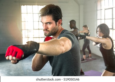 Handsome masculine athlete boxer mma fighter training with fitness group punching aerobox