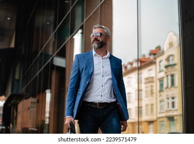 A handsome mature business man is walking through the city street near the office building. - Powered by Shutterstock