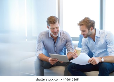 Handsome mature business manager using a digital tablet to discuss something positive with a young employee in a modern business lounge - Powered by Shutterstock