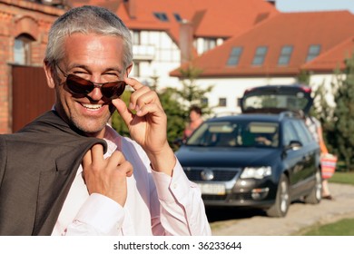 Handsome mature businessman standing in front of house