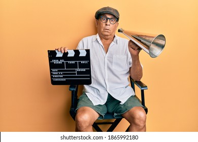 Handsome Mature Director Man Holding Video Film Clapboard And Louder Clueless And Confused Expression. Doubt Concept. 