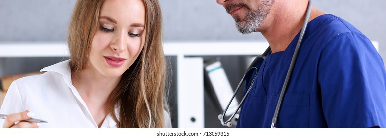 Handsome mature doctor to sign with silver pen portrait. Physical agreement form signature, disease prevention, ward round reception, consent contract sign, prescribe remedy, healthy lifestyle concept - Shutterstock ID 713059315