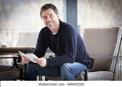 Handsome Mature Happy Man Smiling At The Camera.Outside. Reading A Book