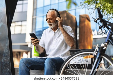 Handsome mature man listening his favorite music on a park bench. Senior man listening his favorite song with bike nearby. - Powered by Shutterstock