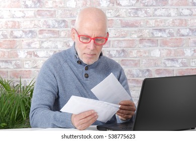 handsome mature man opening letter envelope in his office