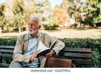 Handsome mature man reading book outdoors. - Powered by Shutterstock