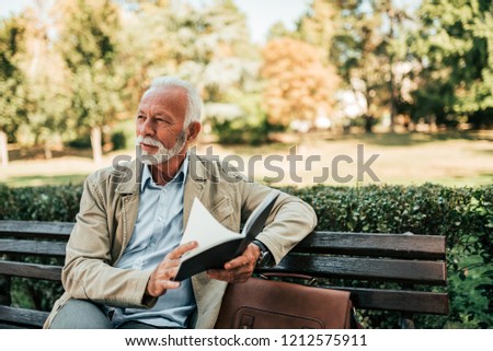 Handsome mature man reading book outdoors.