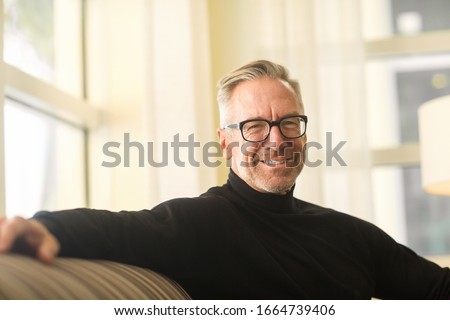 Handsome mature man smiling sitting on a sofa