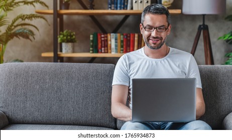 Handsome Mature Man Using His Laptop While Relaxing On Sofa At Home.