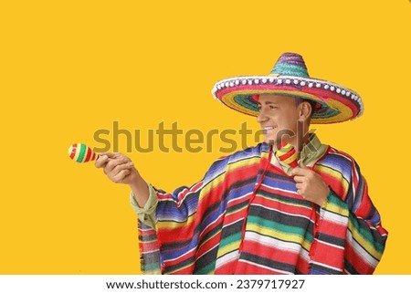 Handsome mature Mexican man in sombrero hat with maracas on yellow background