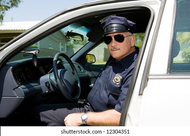 Handsome Mature Police Officer On Duty Sitting In His Squad Car.