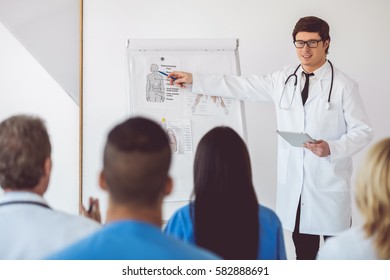 Handsome Medical Doctor Is Giving Lecture For His Colleagues Using A Whiteboard And Schemes