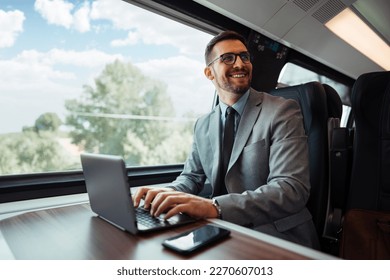 Handsome middle age businessman using his laptop computer while traveling with high-speed train. Modern and fast travel concept. - Powered by Shutterstock