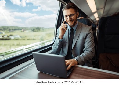 Handsome middle age businessman using his laptop computer while traveling with high-speed train. Modern and fast travel concept.