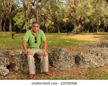 Handsome Middle Age Hispanic Man In A Park Setting.