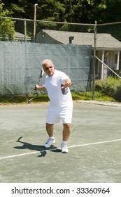 Handsome Middle Age Male Tennis Player Hitting Forehand Stroke On Tennis Court At Club