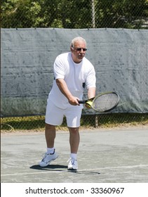 Handsome Middle Age Male Tennis Player Hitting Forehand Stroke On Tennis Court At Club