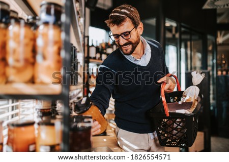 Handsome middle age man buying some healthy food and drink in modern supermarket or grocery store. Lifestyle and consumerism concept.