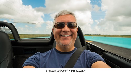 Handsome Middle Age Man Driving A Convertible Automobile On The Highway.