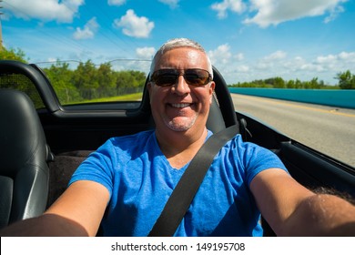 Handsome Middle Age Man Driving A Convertible Automobile On The Highway.