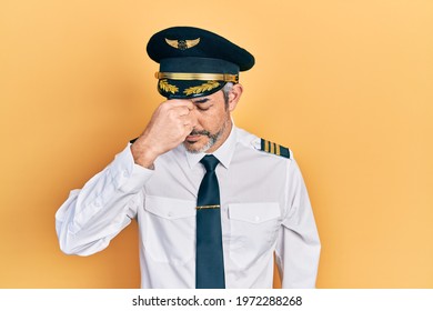 Handsome Middle Age Man With Grey Hair Wearing Airplane Pilot Uniform Tired Rubbing Nose And Eyes Feeling Fatigue And Headache. Stress And Frustration Concept. 