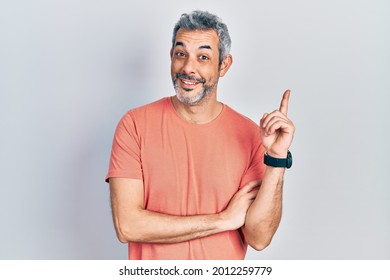 Handsome Middle Age Man With Grey Hair Wearing Casual T Shirt With A Big Smile On Face, Pointing With Hand And Finger To The Side Looking At The Camera. 