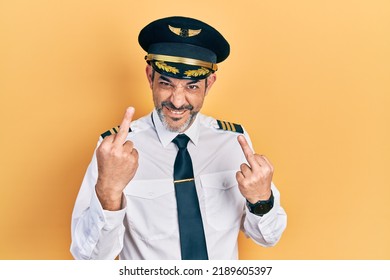 Handsome Middle Age Man With Grey Hair Wearing Airplane Pilot Uniform Showing Middle Finger Doing Fuck You Bad Expression, Provocation And Rude Attitude. Screaming Excited 