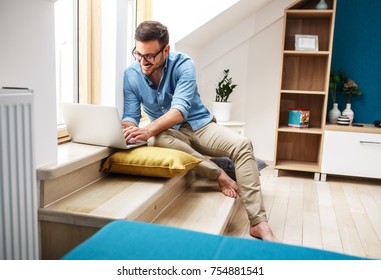 Handsome Middle Age Man Sitting In His Apartment In Living Room By The Window.He Using Laptop .