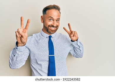 Handsome Middle Age Man Wearing Business Shirt And Tie Smiling Looking To The Camera Showing Fingers Doing Victory Sign. Number Two. 