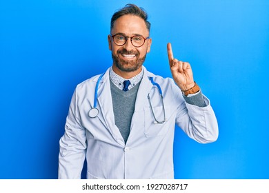 Handsome middle age man wearing doctor uniform and stethoscope showing and pointing up with finger number one while smiling confident and happy. 