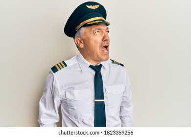 Handsome Middle Age Mature Man Wearing Airplane Pilot Uniform Angry And Mad Screaming Frustrated And Furious, Shouting With Anger. Rage And Aggressive Concept. 