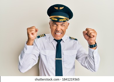 Handsome Middle Age Mature Man Wearing Airplane Pilot Uniform Angry And Mad Raising Fists Frustrated And Furious While Shouting With Anger. Rage And Aggressive Concept. 