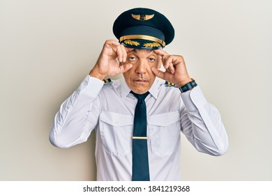 Handsome Middle Age Mature Man Wearing Airplane Pilot Uniform Trying To Open Eyes With Fingers, Sleepy And Tired For Morning Fatigue 