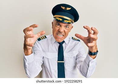 Handsome Middle Age Mature Man Wearing Airplane Pilot Uniform Shouting Frustrated With Rage, Hands Trying To Strangle, Yelling Mad 