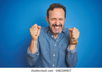 Handsome Middle Age Senior Man With Grey Hair Over Isolated Blue Background Excited For Success With Arms Raised And Eyes Closed Celebrating Victory Smiling. Winner Concept.