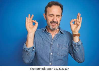 Handsome Middle Age Senior Man With Grey Hair Over Isolated Blue Background Relaxed And Smiling With Eyes Closed Doing Meditation Gesture With Fingers. Yoga Concept.