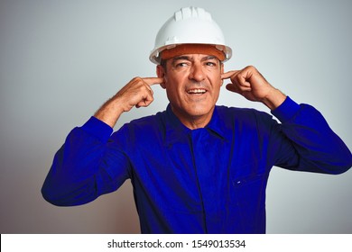 Handsome Middle Age Worker Man Wearing Uniform And Helmet Over Isolated White Background Covering Ears With Fingers With Annoyed Expression For The Noise Of Loud Music. Deaf Concept.