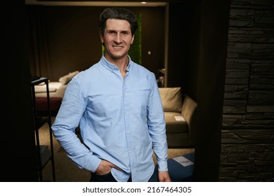 Handsome Middle Aged Caucasian Man - Businessman, Entrepreneur, Interior Designer, Sales Manager In Casual Blue Shirt, Smiles Looking At Camera, Standing At His Workplace In A Furniture Design Store