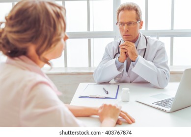 Handsome Middle Aged Doctor Is Offering Consultation To Woman, At Doctors Office