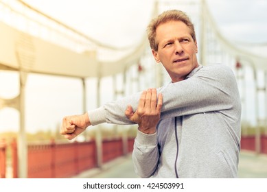 Handsome Middle Aged Man In Sports Uniform Is Looking Away And Warming Up During Morning Run