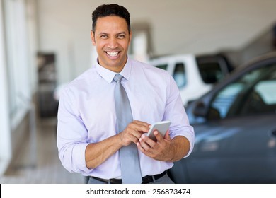 Handsome Middle Aged Man Using Smart Phone At Car Dealership