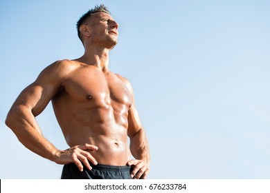 Handsome middle aged man working out on a running track. Healthy adult man sun baiting. Tanned skin and shirtless middle-aged man. - Powered by Shutterstock