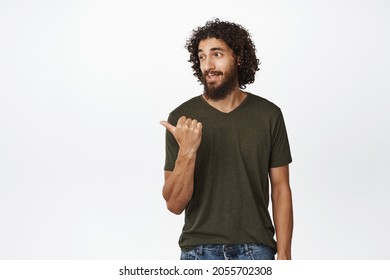 Handsome middle easter bearded man, pointing and looking left, sassy face expression, showing website banner, advertisement on copy space, white background